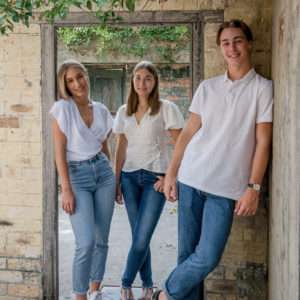 Three siblings in casual white and denim outfits in an urban laneway, family portrait by Twin Lotus Production, Brisbane family photographer