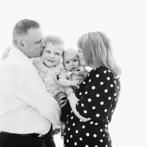 Parents embracing their toddler and baby in a black-and-white family portrait by Twin Lotus Production, Brisbane family photographer