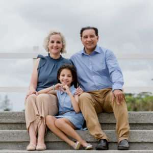 Parents smiling with their daughter in coordinated blue outfits during a Brisbane family portrait session by Twin Lotus Production, Brisbane family photographer