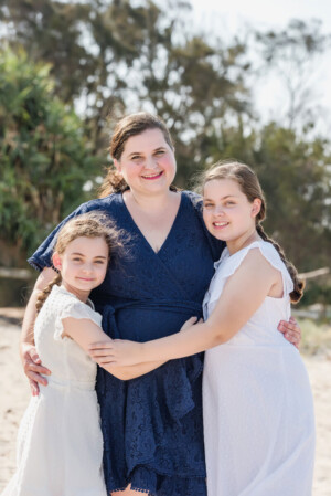 Mum embracing her two daughters on the beach at Wynnum Manly, family portrait session by Twin Lotus Production, Brisbane family photographer