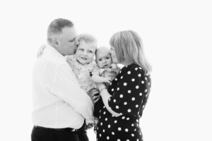 Parents embracing their toddler and baby in a black-and-white family portrait by Twin Lotus Production, Brisbane family photographer
